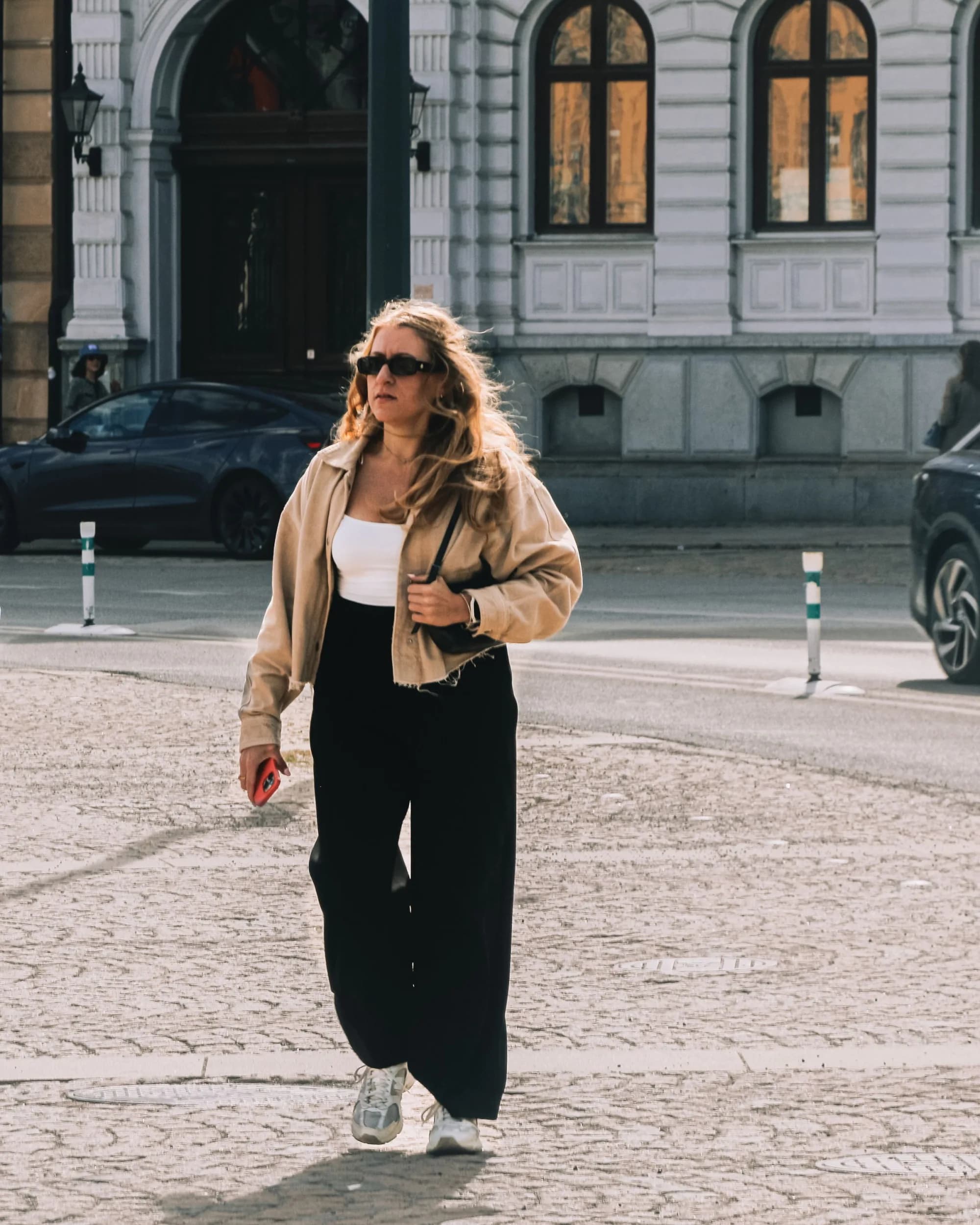A woman walking between shopfronts on a city street
