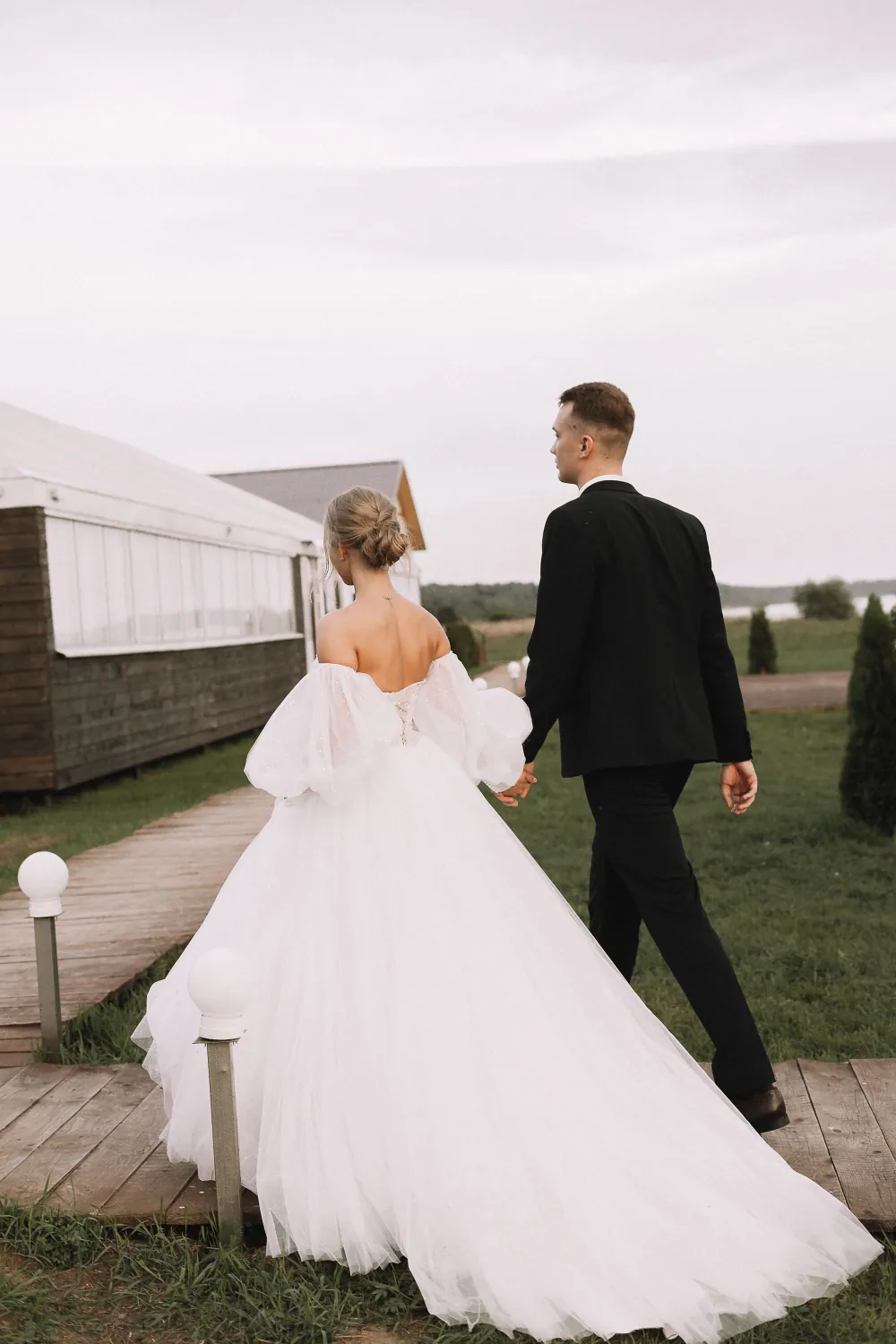 A bride and groom walking hand in hand along a path on their wedding day