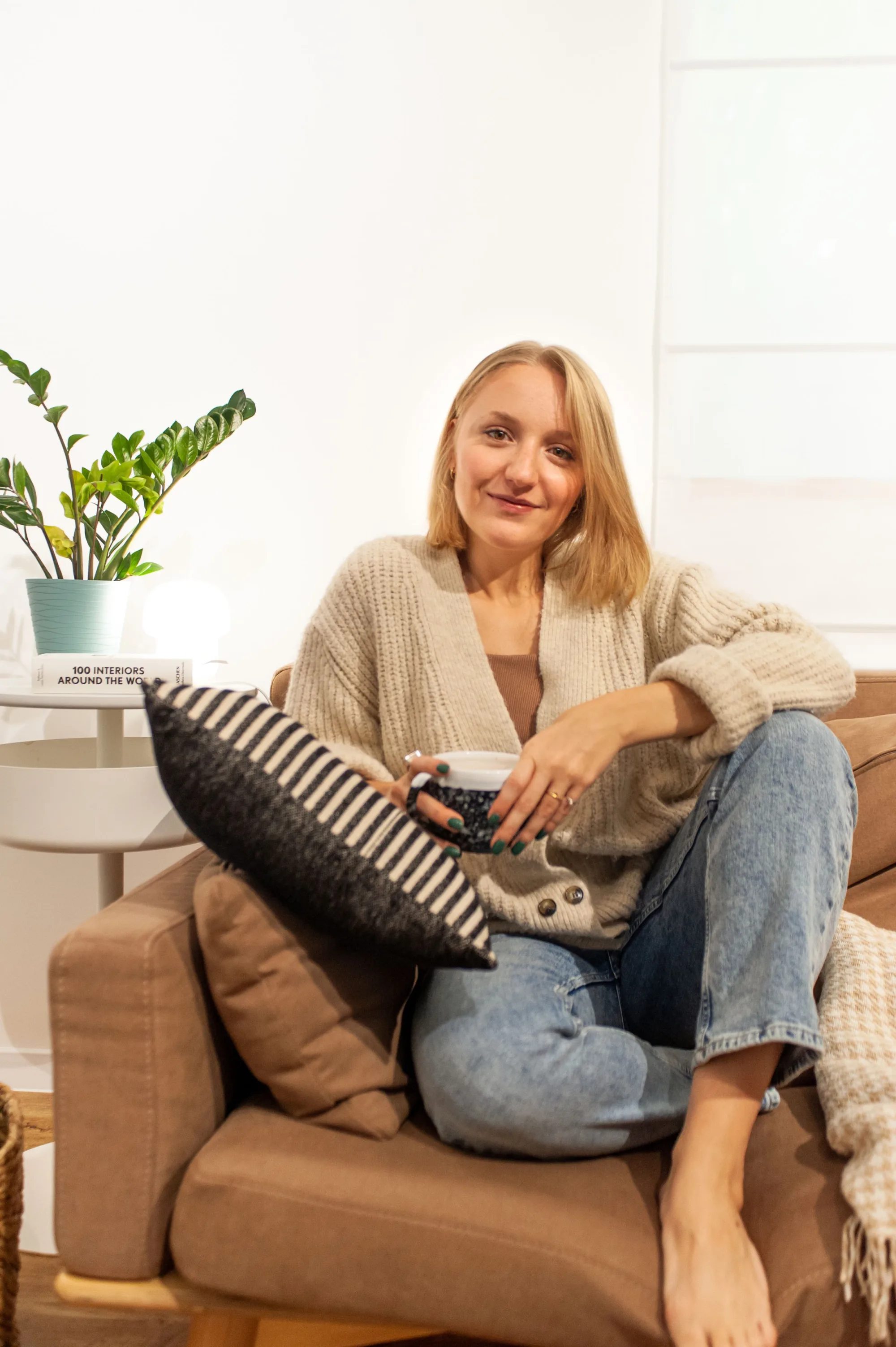 A salon owner at rest in an armchair with a cup and her phone