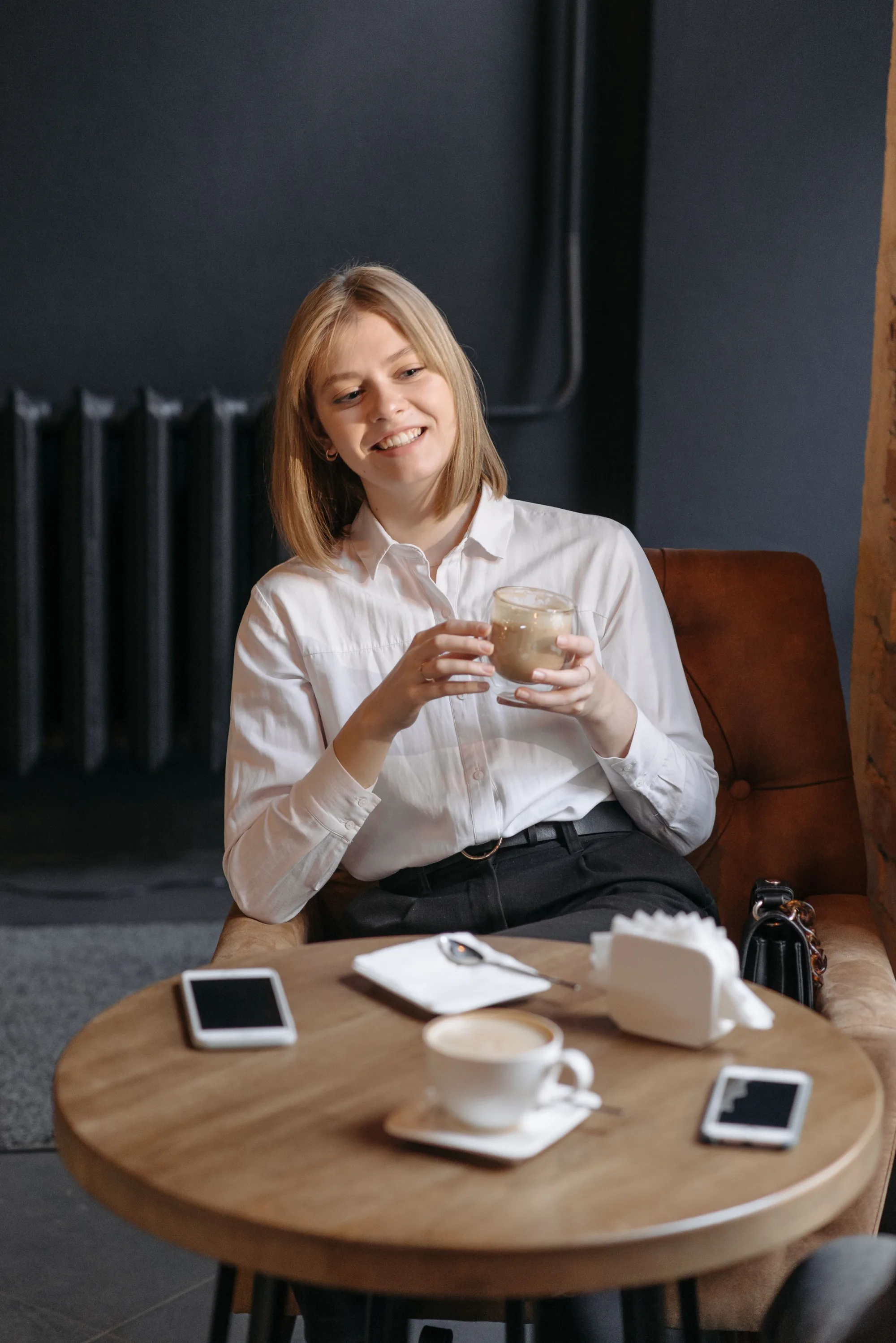 A woman booking on her phone over a coffee