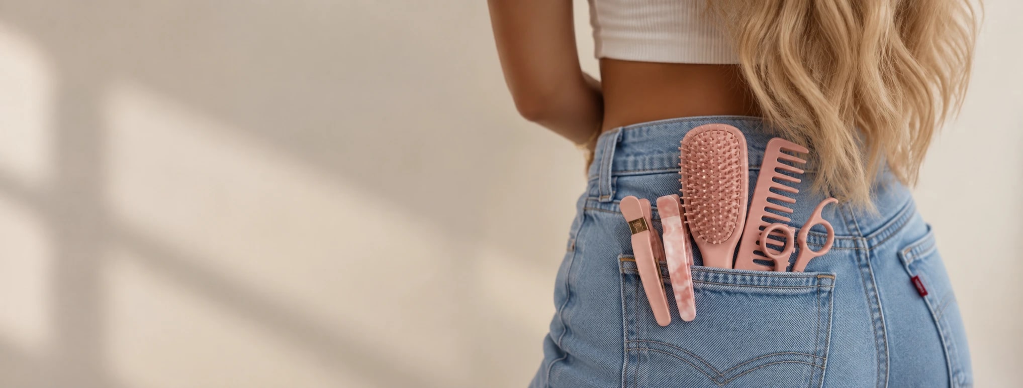 Pink hair and makeup tools tucked into the back pocket of blue jeans
