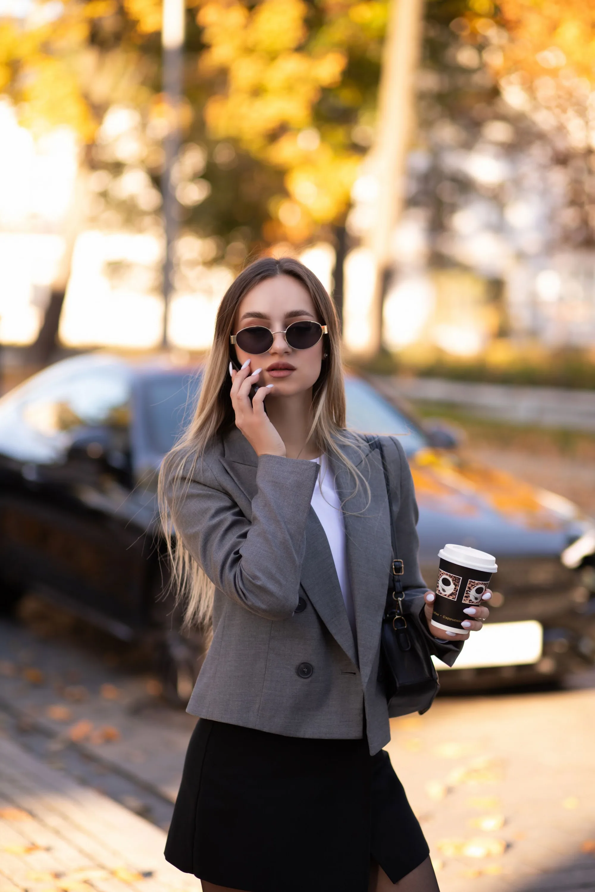 A woman on the phone in the street with a coffee