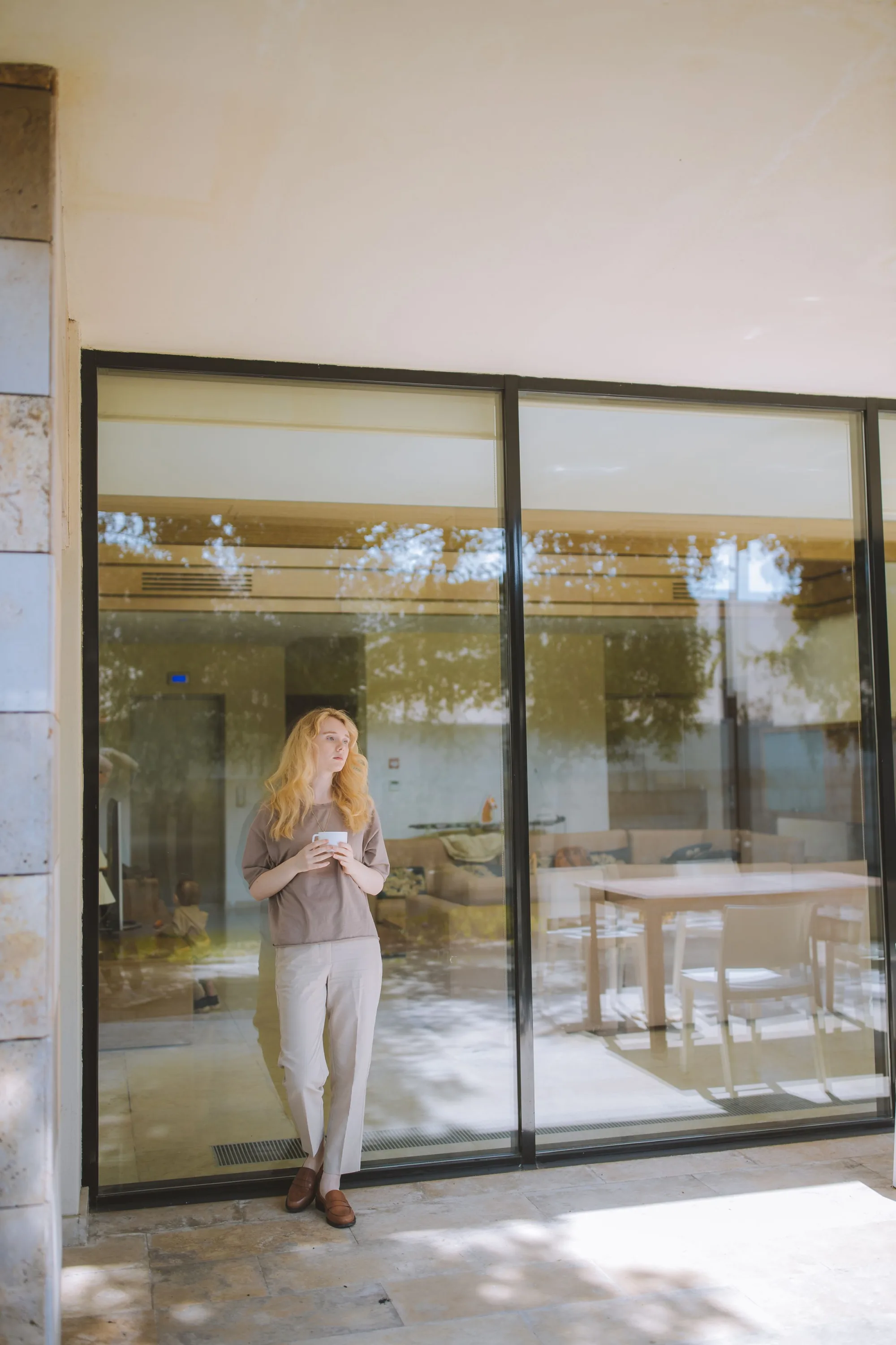 A woman with a coffee outside a glass-walled building