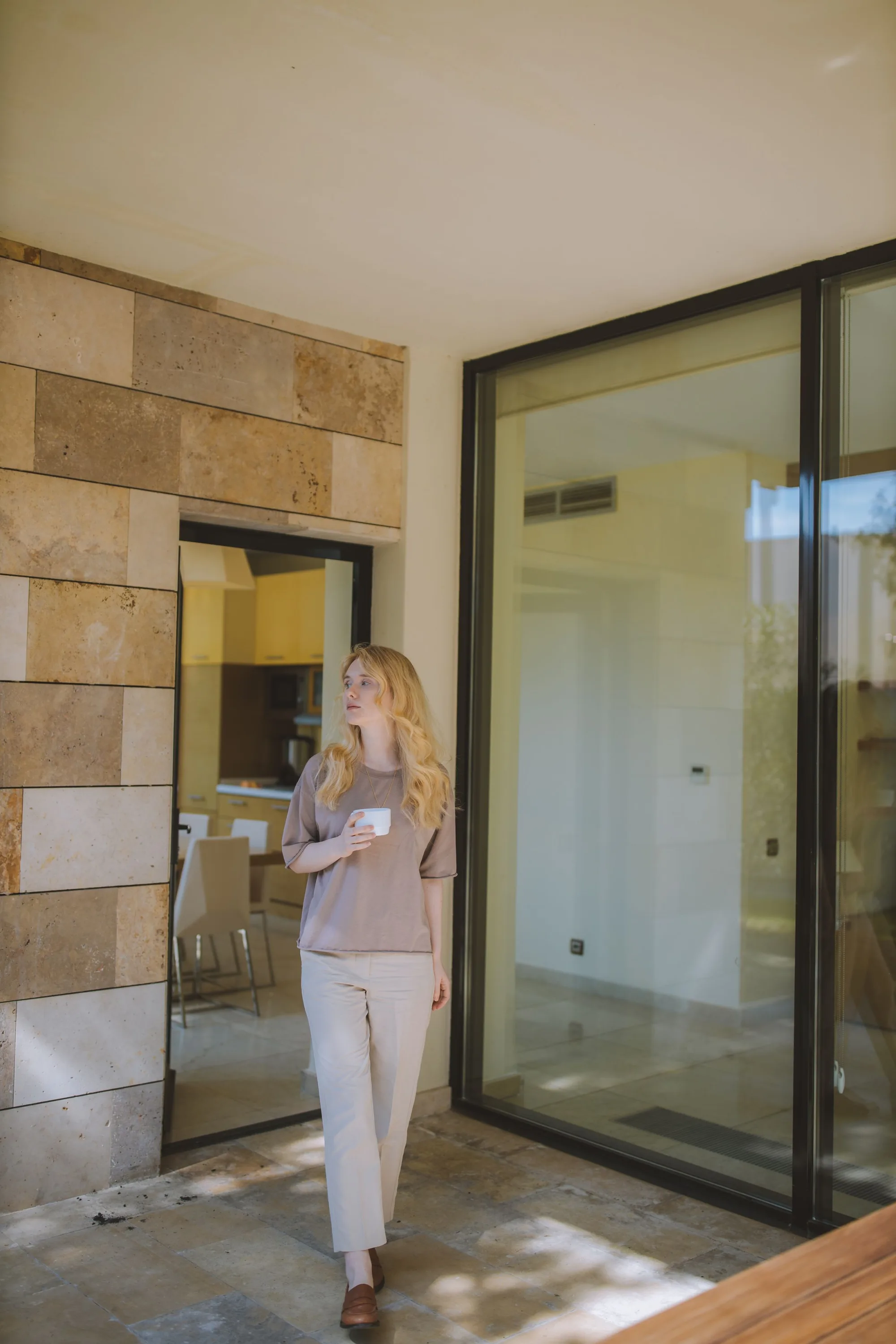 A woman walking past a glass wall with a coffee
