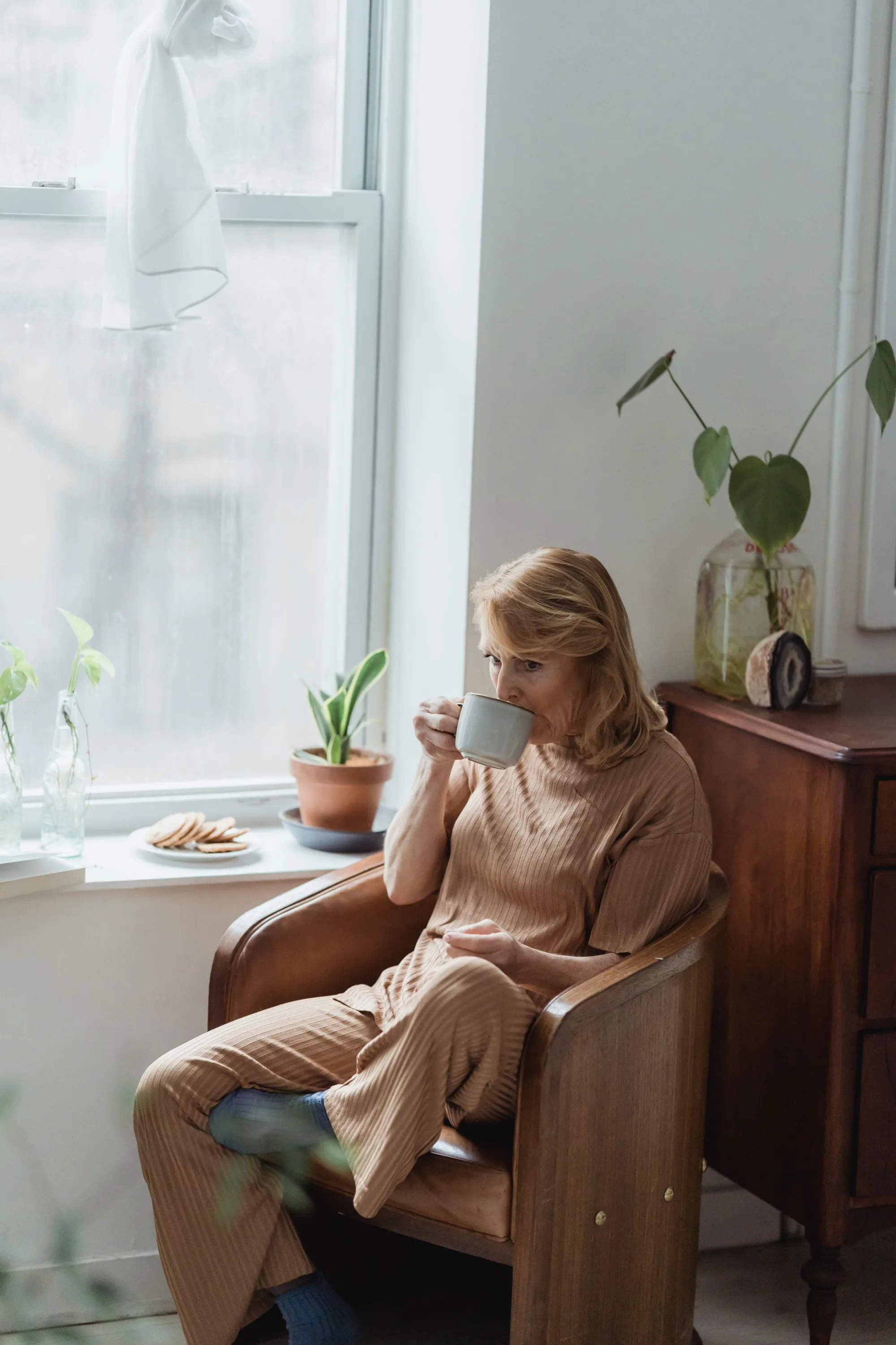 A woman reading by a window with a mug