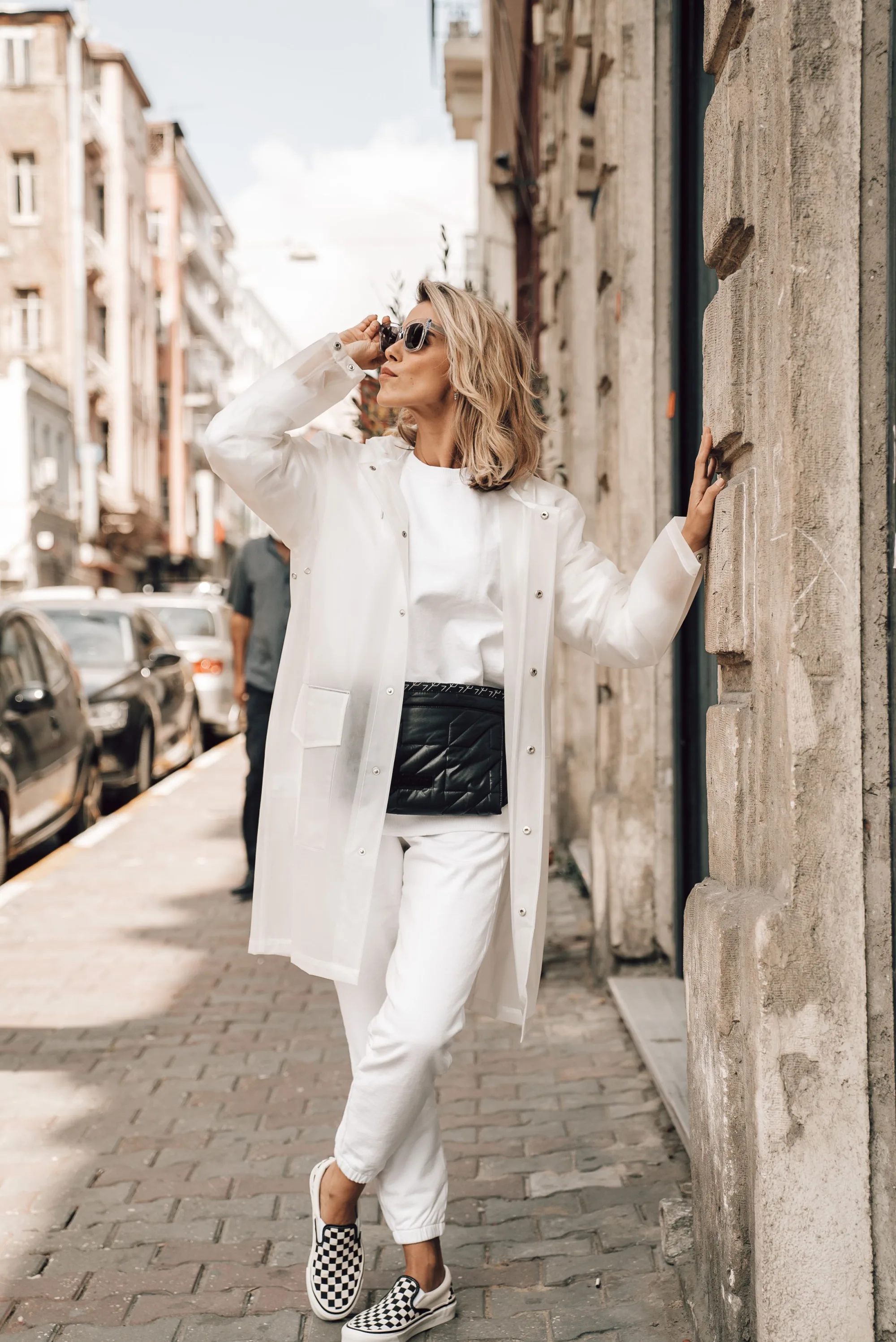 A woman reading her phone on a white city street