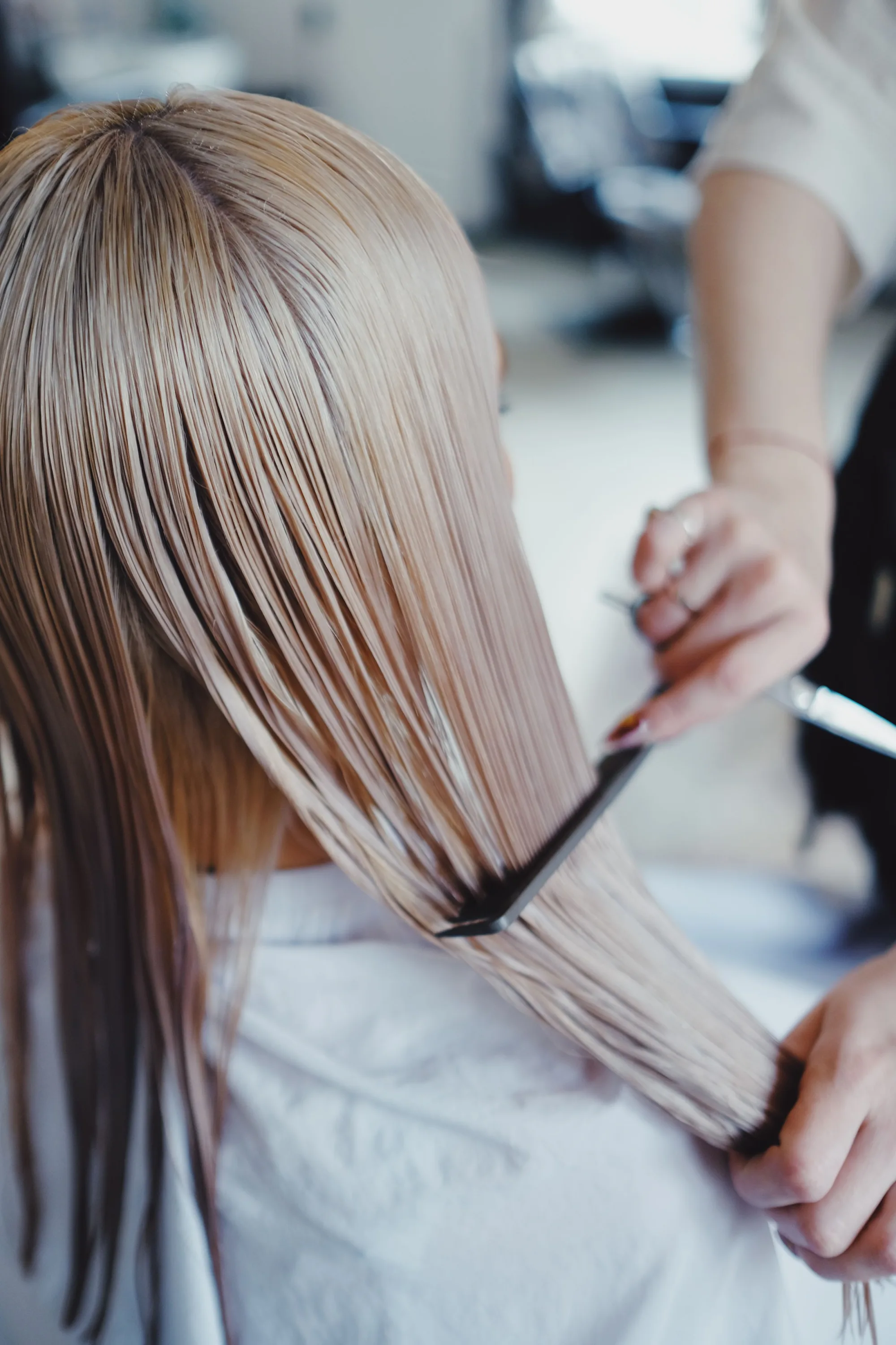 A stylist combing through a client's long blonde lengths