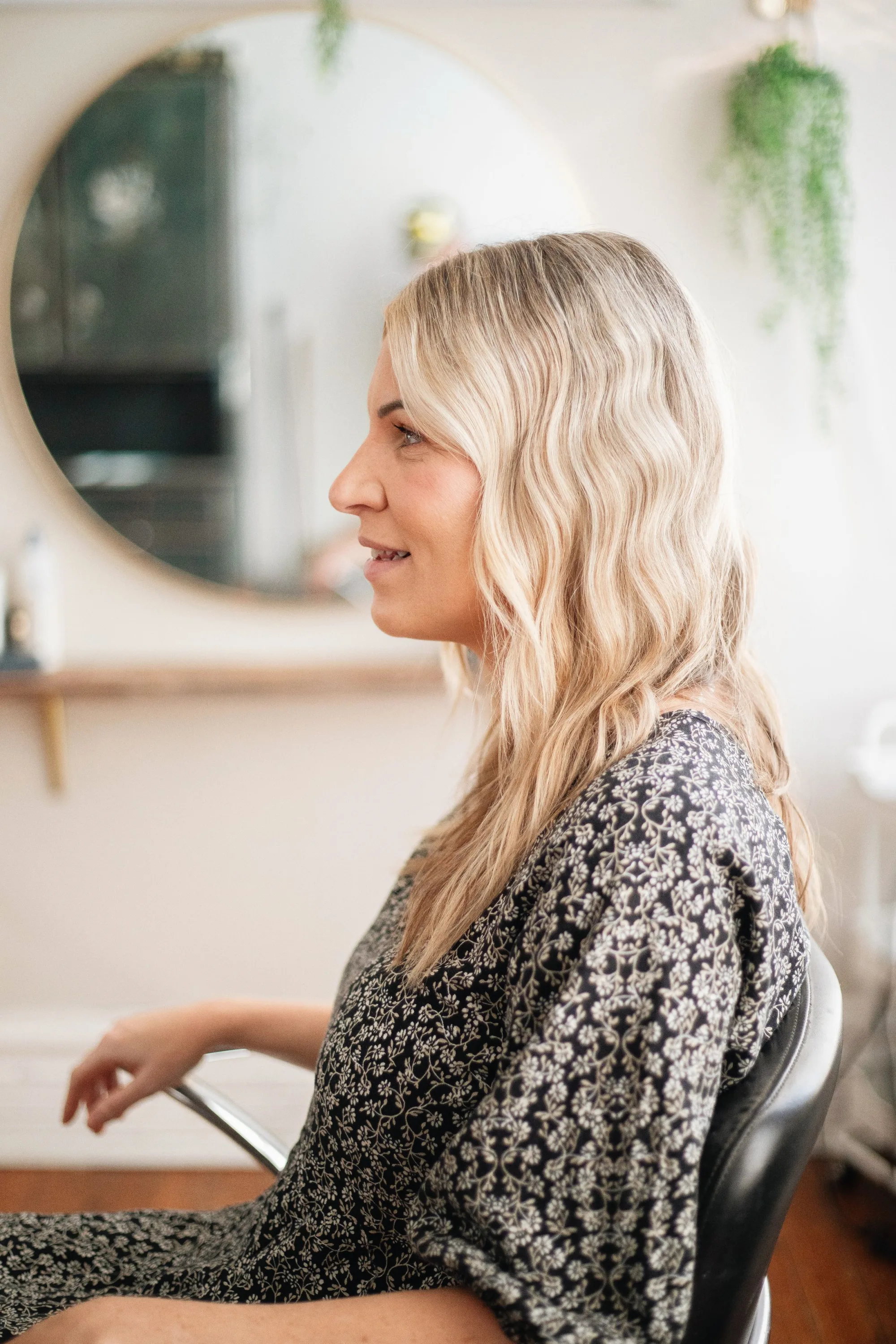 A salon owner in profile beside her mirror