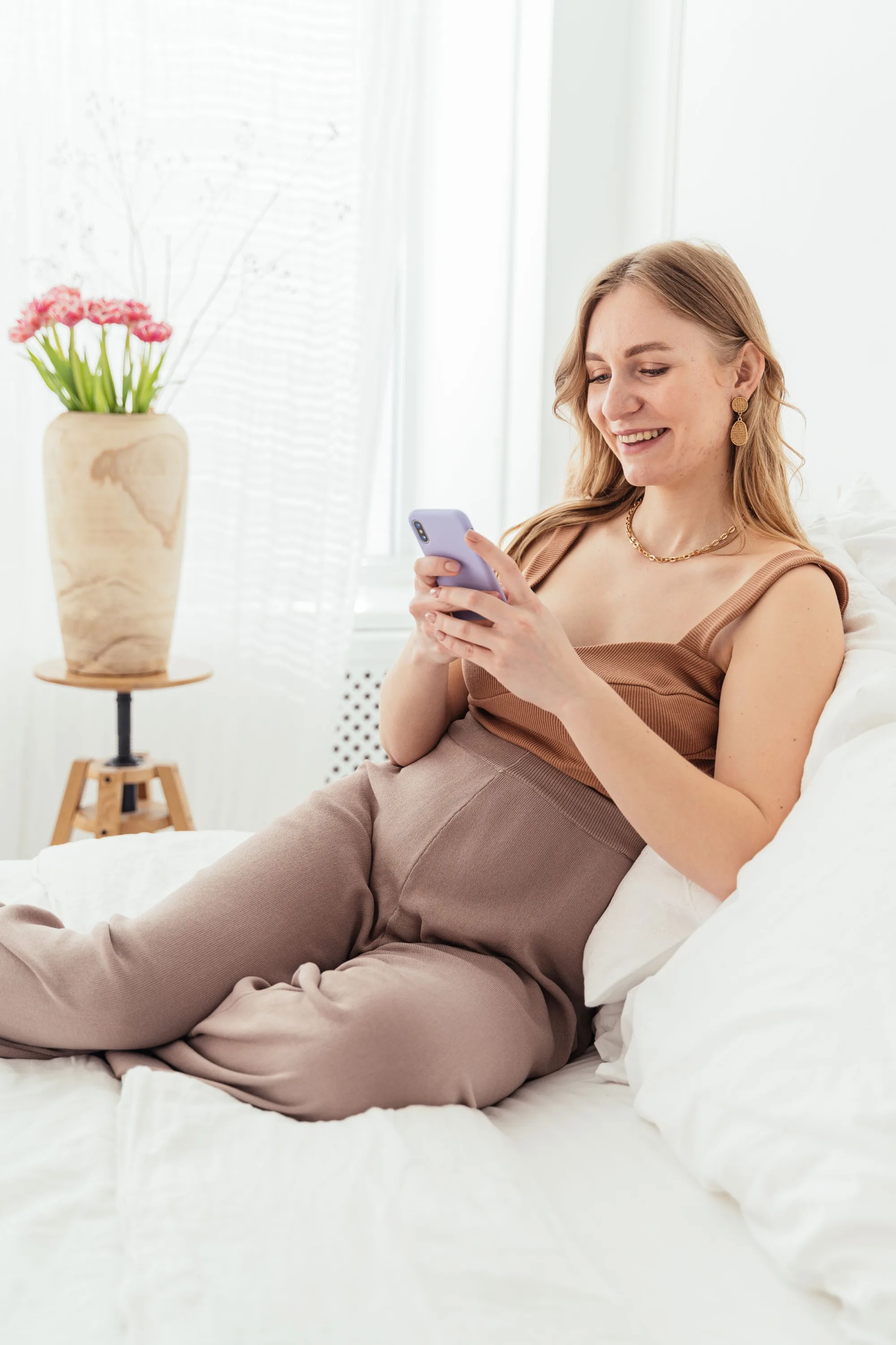 A salon owner smiling at her phone on the sofa