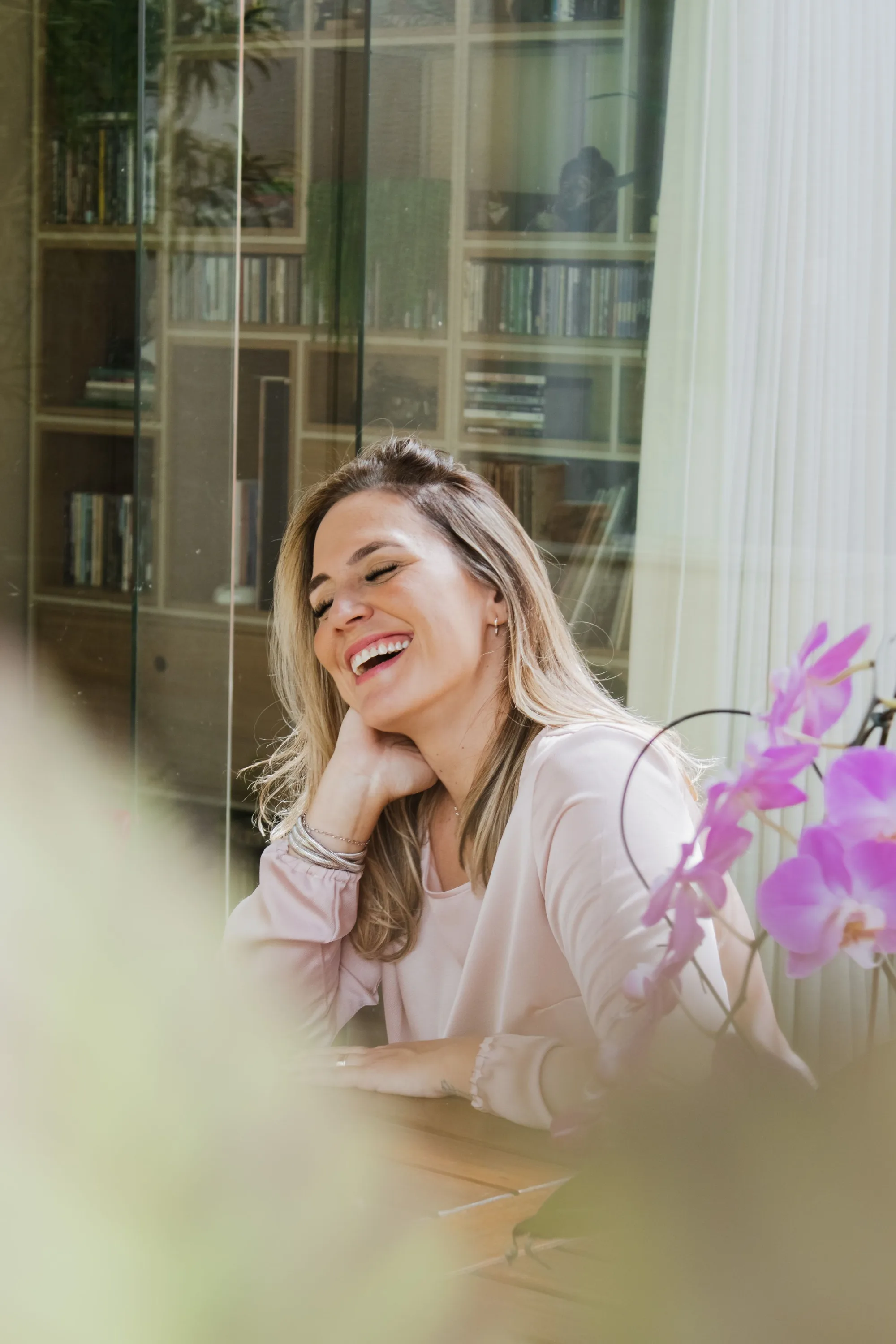 A woman laughing at a table with flowers