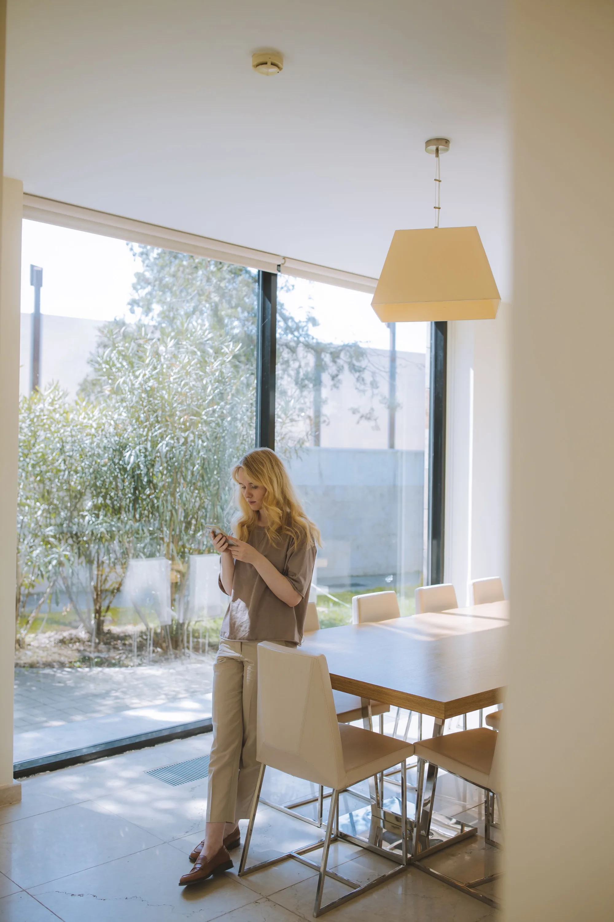 A woman by a tall window in a bright room