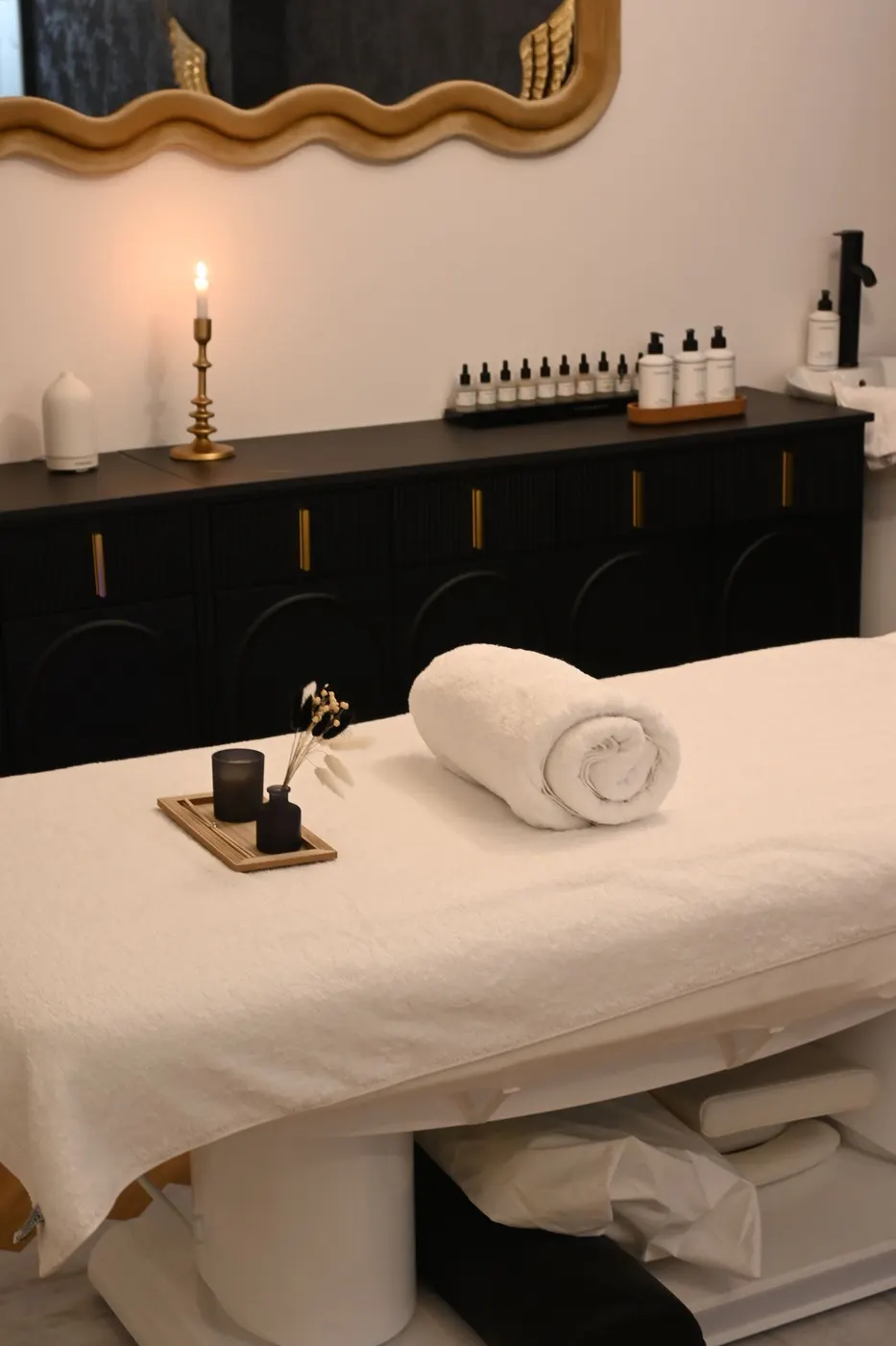 A treatment bed with a folded towel and a candle